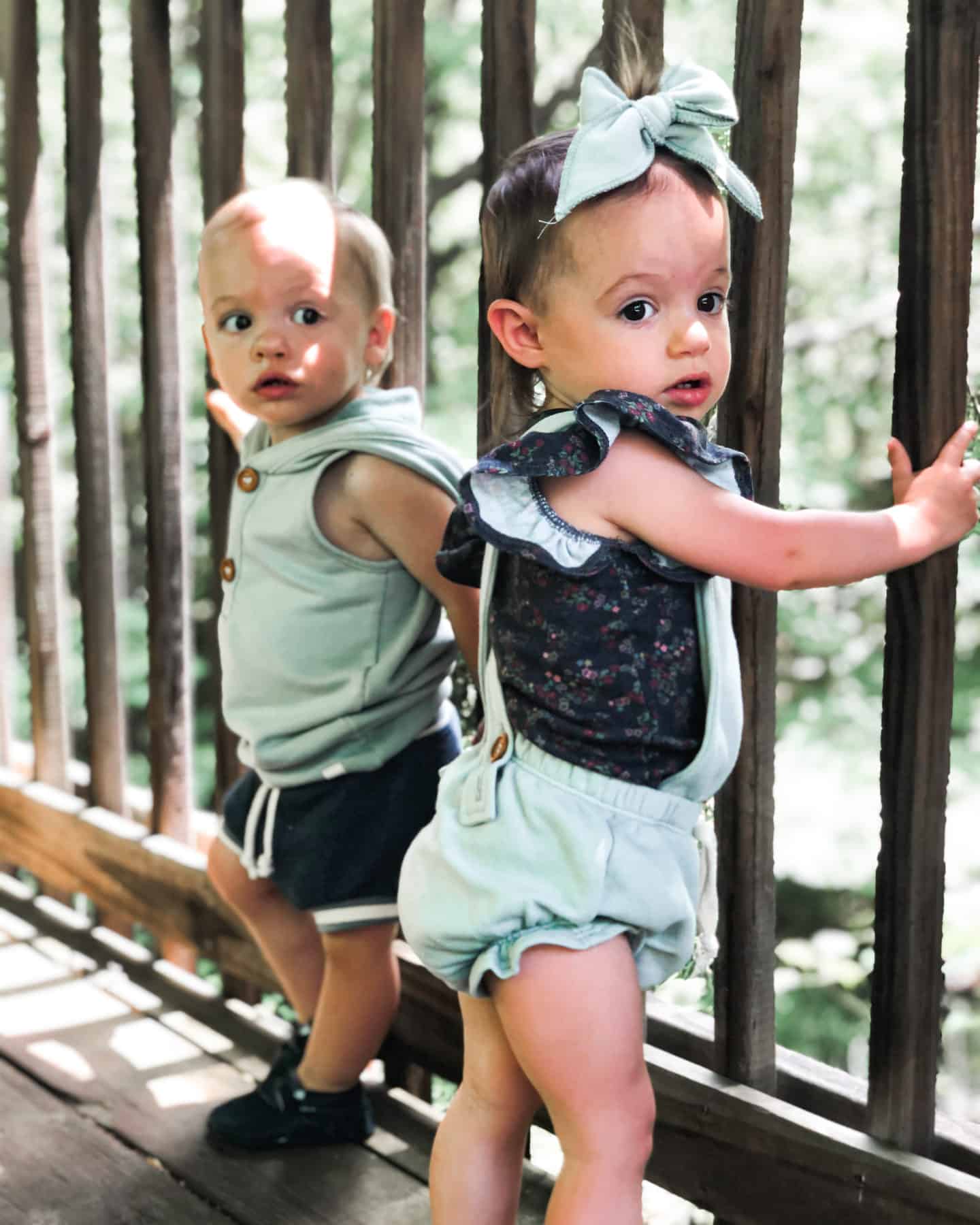 shopping with twins, boy and girl in mint and navy blue outfits standing on bridge